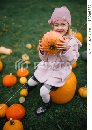 Happy child with pumpkin enjoys autumn day at a farm surrounded by harvest decorations Happy child with pumpkin enjoys autumn day at a farm surrounded by harvest decorations 131006732