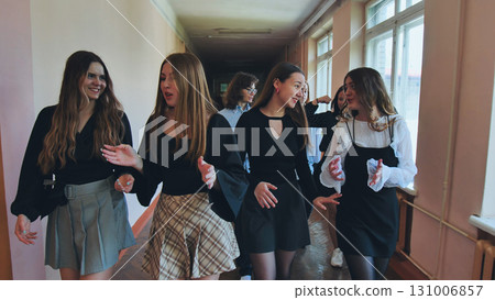 Group of teenage high school students walking down school hallway, chatting and gesturing 131006857