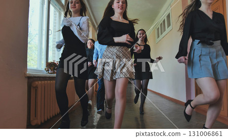 High school girls and teacher happily running in school hallway during break, cherishing their youth and friendship 131006861