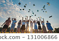 Group of cheerful students throwing their notebooks in the air celebrating the end of school, backlit by setting sun 131006866
