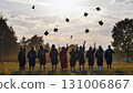 Group of graduates throwing mortarboards in the air at sunset, celebrating their academic achievement and the end of their studies 131006867
