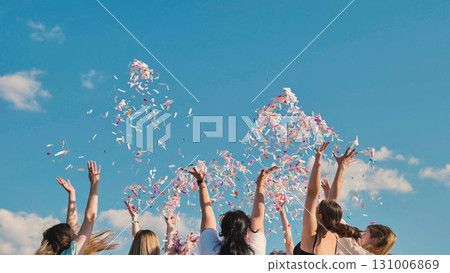 Students celebrating their graduation by tossing colorful confetti into the summer sky Students celebrating their graduation by tossing colorful confetti into the summer sky 131006869