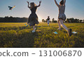 High school girls having fun running in a field at sunset, tossing paper airplanes during their summer break 131006870