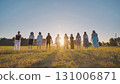 High school students gather in a sunlit field at sunset, sharing laughter and joy as they celebrate the start of summer break 131006871