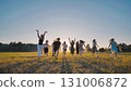 Happy friends gleefully running towards the camera in a sunlit field at sunset, embodying the carefree youth lifestyle with joy and cheer 131006872