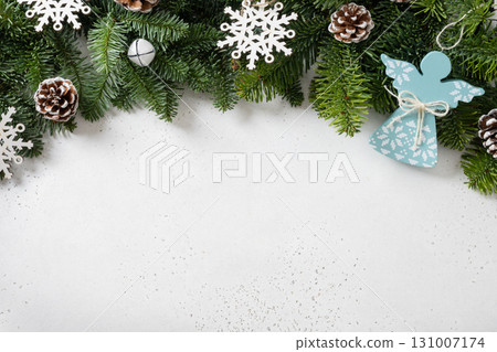 Christmas frame with evergreen branches and angel of wooden natural materials, snowflakes on white background. Copy space. Xmas greeting card. Winter Holiday. View from above. 131007174