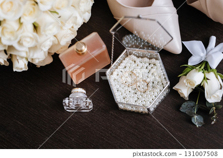 Elegant wedding rings in pearl box with perfume, roses and bridal accessories Elegant wedding rings in pearl box with perfume, roses and bridal accessories 131007508