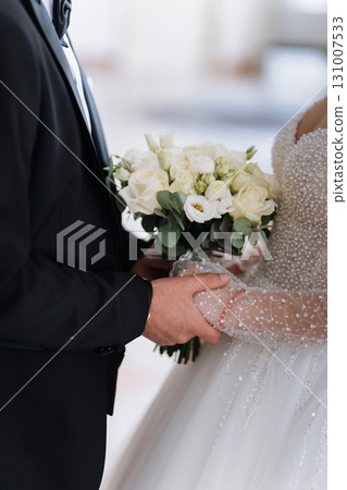 Elegant bride and groom holding wedding bouquet and hands on their wedding day 131007533