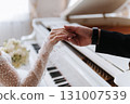 Elegant wedding moment of bride and groom gently holding hands near white piano 131007539