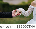 Groom gently holding brides hand in wedding dress with pearl sleeves, outdoor close up 131007540