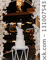 Elegant white wedding cake with sugar floral decor on modern stand at luxury reception 131007543