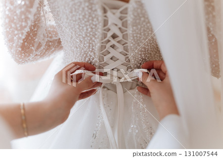 Bridal dress back lacing close up on wedding morning preparation moment 131007544