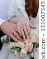 Wedding rings on bride and grooms hands over elegant bouquet of white roses 131007545