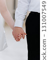 Close up of bride and groom holding hands in elegant wedding attire 131007549