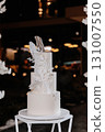 Elegant white wedding cake with sugar floral decor on modern stand at luxury reception 131007550