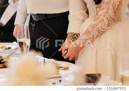Bride and groom holding hands at wedding dinner, elegant and emotional close up moment Bride and groom holding hands at wedding dinner, elegant and emotional close up moment 131007551