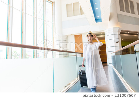 A woman walking down an airport corridor 131007607