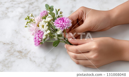 Hands arranging a beautiful bouquet of pastel flowers on a marble surface Hands arranging a beautiful bouquet of pastel flowers on a marble surface 131008048