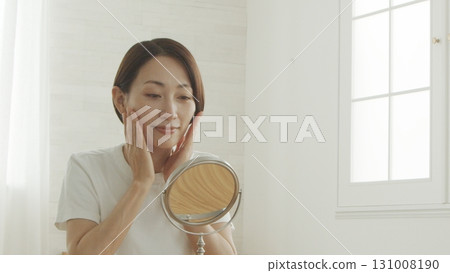 A Japanese woman in her 40s checking her skin condition in front of the mirror 131008190