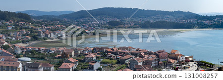 Hundreds harvest shellfish at low tide in a Galician estuary, seen from above. 131008257