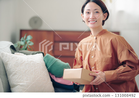 一位 40 多歲的日本女性手裡拿著一件網購商品 131008492