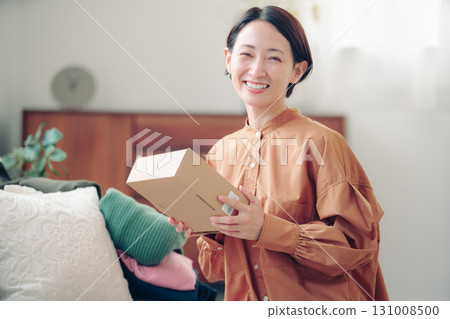 一位 40 多歲的日本女性手裡拿著一件網購商品 一位 40 多歲的日本女性手裡拿著一件網購商品 131008500