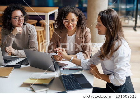 A group of diverse women engaging in collaboration within a thriving modern office environment A group of diverse women engaging in collaboration within a thriving modern office environment 131008525