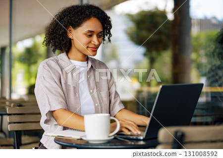 A Focused Young Woman Working Diligently on Her Laptop in a Cozy Cafe Environment A Focused Young Woman Working Diligently on Her Laptop in a Cozy Cafe Environment 131008592