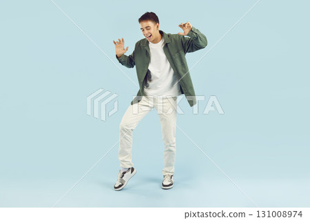 Young happy funny teenage boy having fun isolated on studio blue background. 131008974