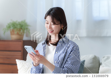 Smiling young woman using a smartphone Smiling young woman using a smartphone 131008979