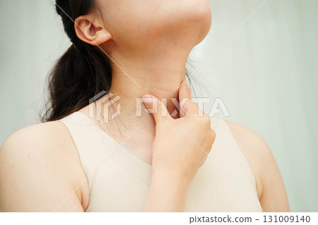 Asian woman touching her neck and throat for thyroid gland problem. Asian woman touching her neck and throat for thyroid gland problem. 131009140