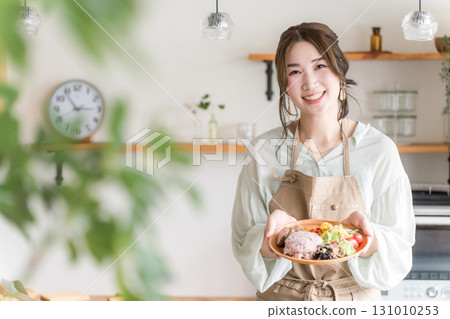 一位家庭主婦在廚房準備一盤午餐 一位家庭主婦在廚房準備一盤午餐 131010253
