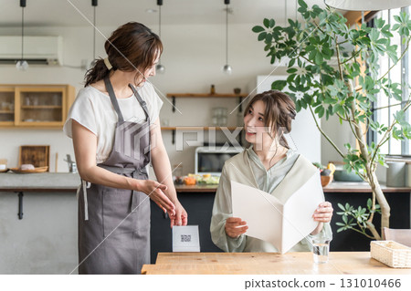 一位年輕的亞洲女士在咖啡館裡一邊看菜單一邊點餐。 一位年輕的亞洲女士在咖啡館裡一邊看菜單一邊點餐。 131010466