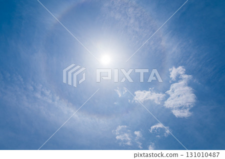 White clouds and sun halo phenomenon in the blue sky 131010487
