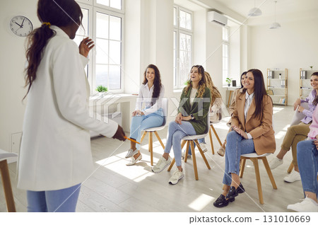 Happy diverse women laughing at funny joke that coach shares during business presentation 131010669