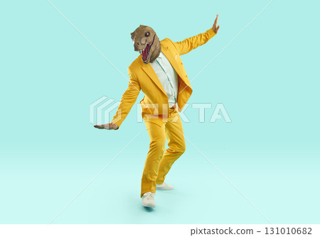 Happy man in yellow suit and funny dinosaur mask balancing on pretend skateboard 131010682
