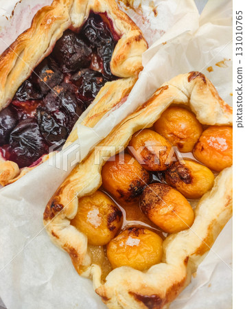Delicious homemade apricot and plum tarts baking on parchment paper Delicious homemade apricot and plum tarts baking on parchment paper 131010765