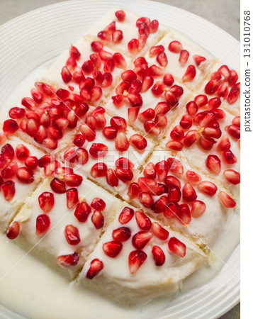 Delicious tres leches milk cake garnished with pomegranate seeds on white plate for birthday Delicious tres leches milk cake garnished with pomegranate seeds on white plate for birthday 131010768