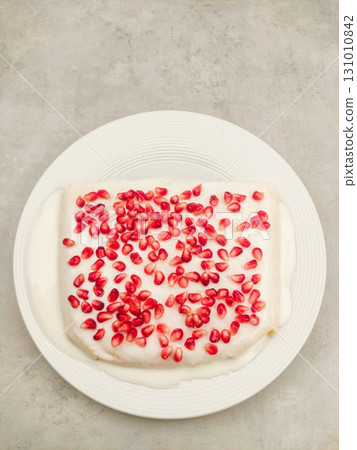 Delicious tres leches milk cake with pomegranate seeds on white plate for birthday Delicious tres leches milk cake with pomegranate seeds on white plate for birthday 131010842