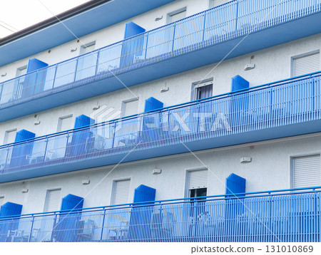 Blue balconies creating rhythmic pattern on white building facade in lignano sabbiadoro 131010869