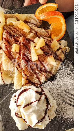 Delicious crepes with pineapple, whipped cream, chocolate topping and orange slices in slovakia strbske pleso, high tatras 131011068