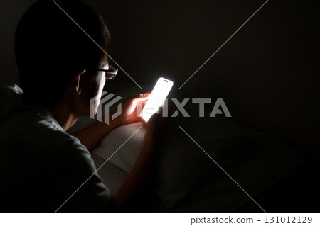 A person using and operating a smartphone in bed before going to sleep Copy space A person using and operating a smartphone in bed before going to sleep Copy space 131012129