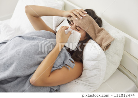 Unhealthy woman sneezes, high temperature, headache feels bad, sick ill, flu or cold, covid-19  131012474