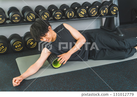 一名年輕的亞洲男子使用泡沫軸放鬆身體側面的筋膜 131012779