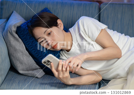 A woman watching a smartphone on a sofa 131012869