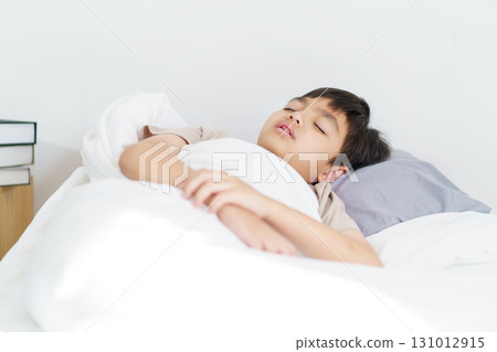 Asian boy wakes up in the early morning, feeling groggy and reluctant to leave the comfort of his bed. He yawns deeply, rubs his sleepy eyes, and stretches his arms and body lazily. Asian boy wakes up in the early morning, feeling groggy and reluctant to leave the comfort of his bed. He yawns deeply, rubs his sleepy eyes, and stretches his arms and body lazily. 131012915