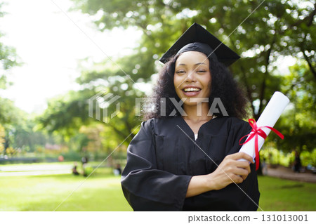 Female student in graduation gown has an excited and delighted expression as she receives her diploma upon graduating from university. African woman feels proud about her academic achievement. 131013001