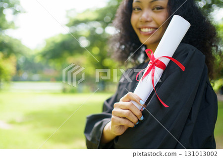 Female student in graduation gown has an excited and delighted expression as she receives her diploma upon graduating from university. African woman feels proud about her academic achievement. Female student in graduation gown has an excited and delighted expression as she receives her diploma upon graduating from university. African woman feels proud about her academic achievement. 131013002