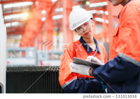 Team of Asian mechanical engineers is having a discussion inside the factory, with the chief engineer talking to his team. Engineer is briefing his team in the morning before they begin their work. 131013038