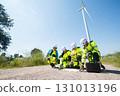 Team of professional electrical engineers in fully safety suit are working and discussing together at the windmill electric generating turbine. Electricians working at the site of windmill turbine. 131013196